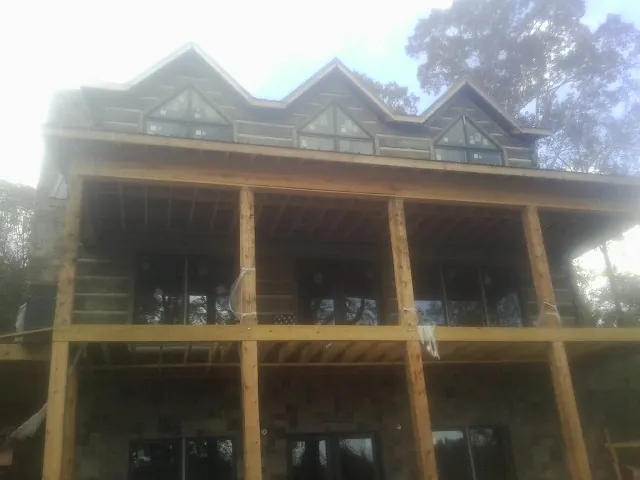 Dormers and porch framing on a large log home under construction — Roof Coating work by our crew in Dacula