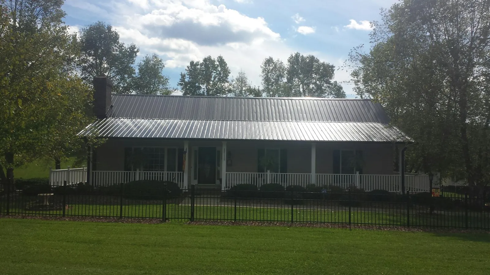 Gray metal roof on a brick ranch with a full width front porch — Gutter Guard Installation work by our crew in Dacula