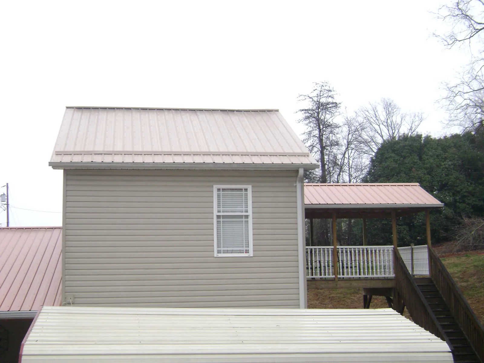Tan metal roofs on a two story addition and attached porch, from a Roof Replacement job in Dacula