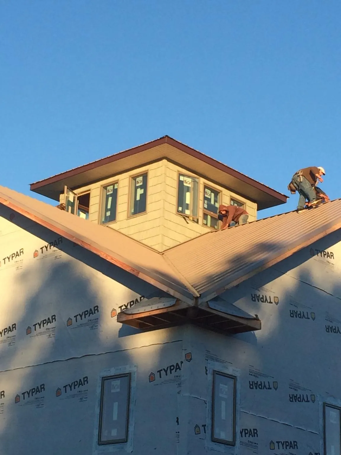 Roofers working around a rooftop cupola on a new metal roof at sunset — Roof Waterproofing in Dacula by Roofing Brothers